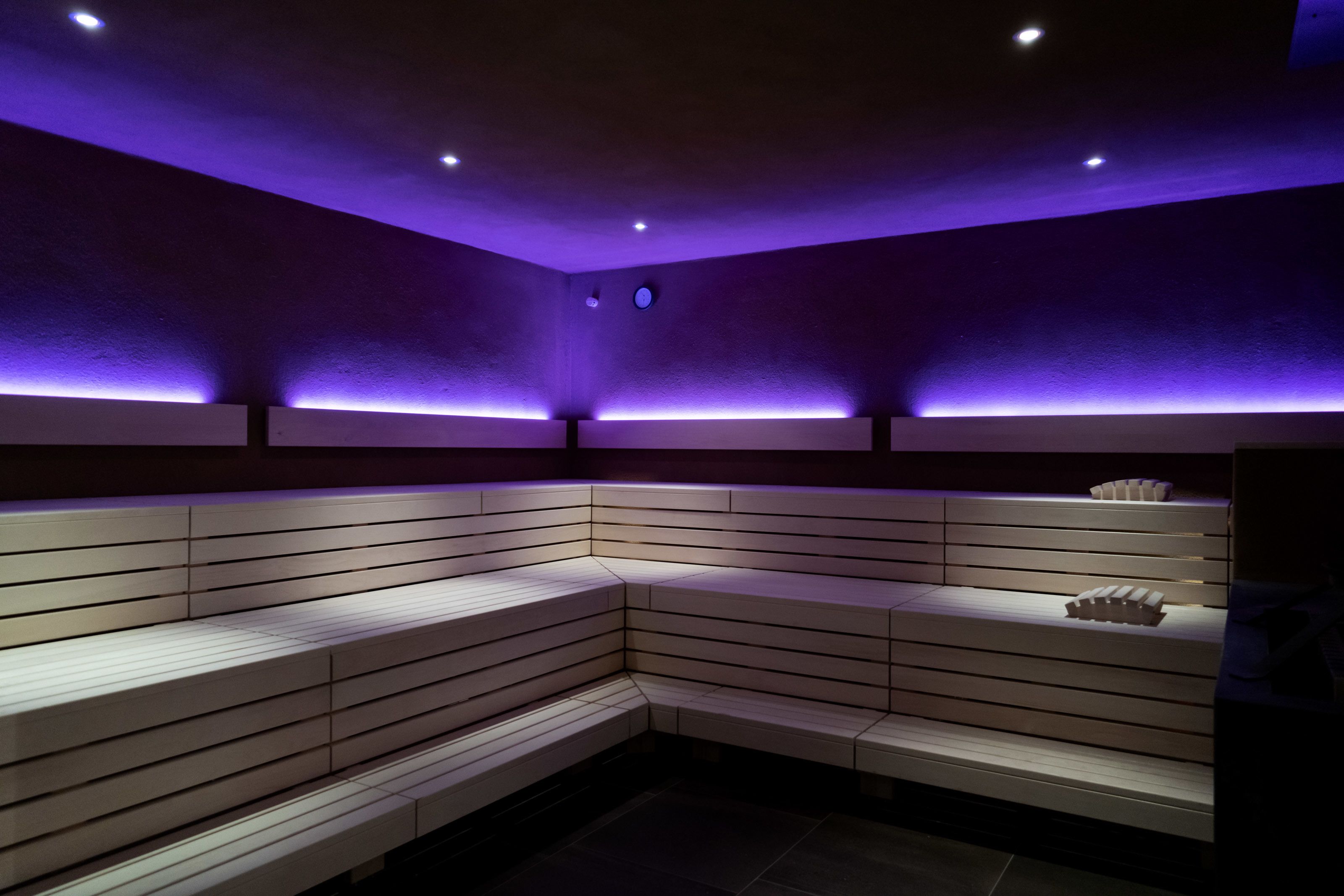 Una habitación moderna, con poca luz, que presenta un banco curvo y una estantería con objetos decorativos.