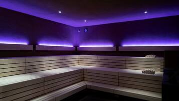 Una habitación moderna, con poca luz, que presenta un banco curvo y una estantería con objetos decorativos.