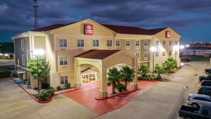 Un hotel Comfort Suites con entrada cubierta, varios espacios de estacionamiento y fachada bien iluminada.