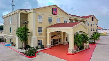 A hotel with a beige facade, a red roof, and a sign indicating it is a Comfort Suites.