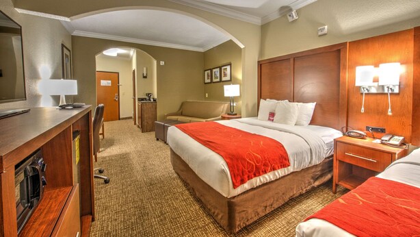 Una habitación de hotel con una cama grande, un escritorio, una silla, una mesita de noche y una lámpara.