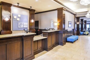 A hotel reception area with a marble counter, a blue bench, and a wall-mounted sign.