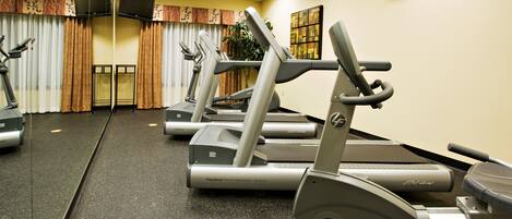 Ein Fitnessraum mit Laufbändern, Ergometer und einer Spiegelwand.