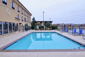 A swimming pool with lounge chairs and a covered seating area.