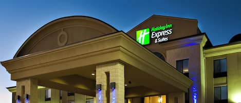 Edificio de Holiday Inn Express & Suites con entrada cubierta y señalización iluminada.