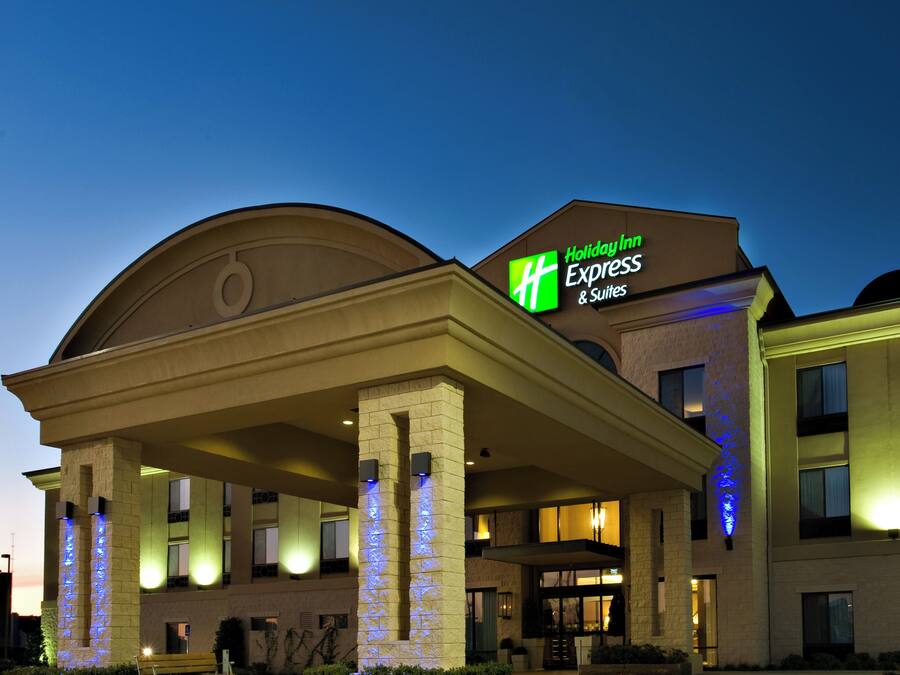 Edificio di un Holiday Inn Express & Suites con ingresso coperto e insegna illuminata.