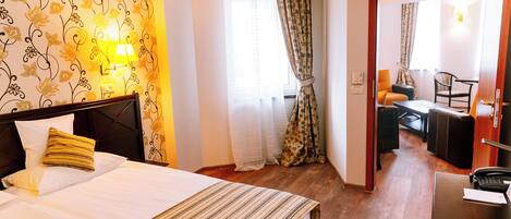 Una habitación de hotel con cama, escritorio, silla y lámpara.