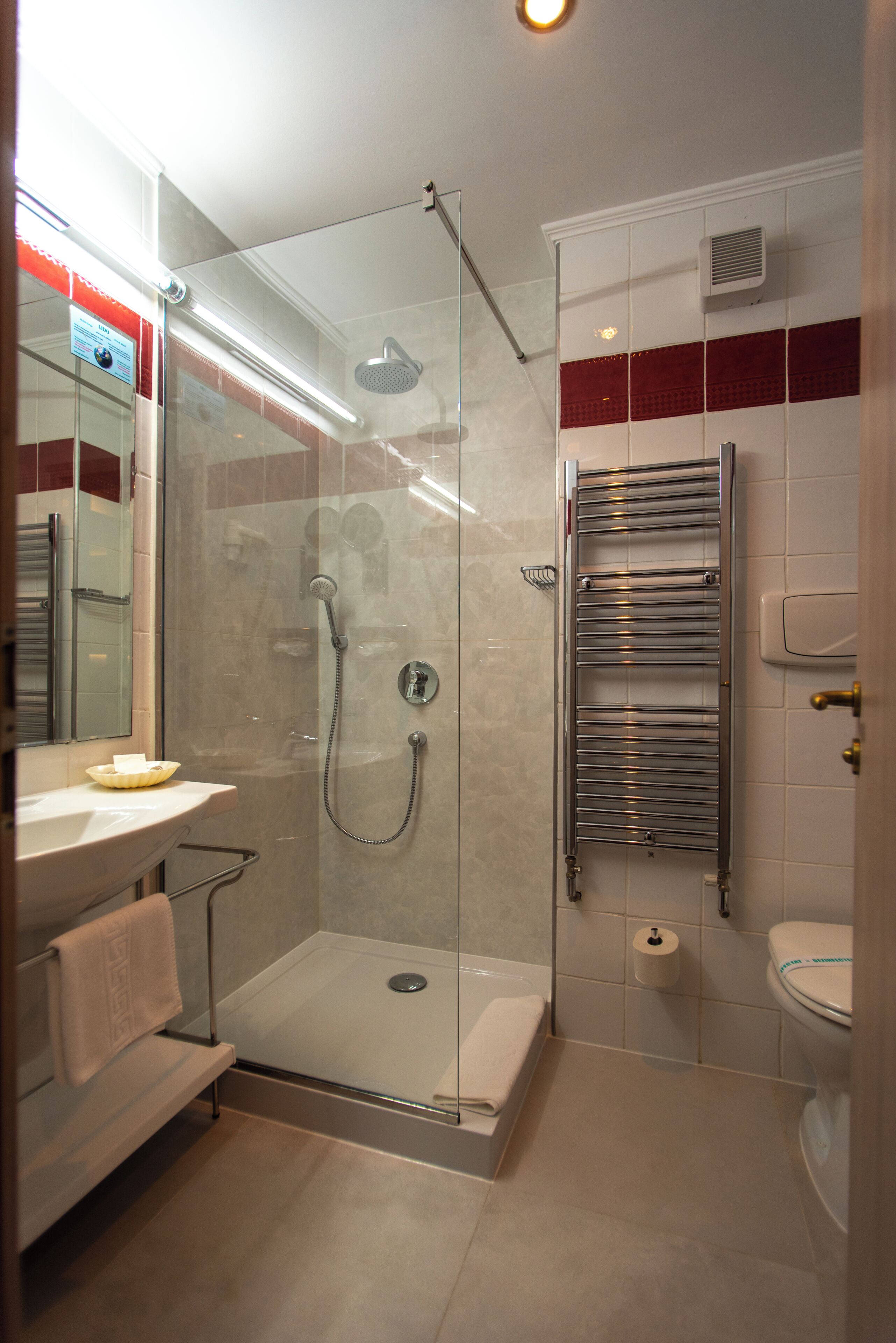 A modern bathroom with a glass-enclosed shower, a white sink, a towel rack, and a toilet.