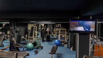 Une salle de sport équipée de matériel d’exercice, d’un téléviseur et d’un ballon d’exercice bleu.