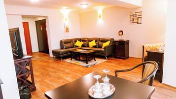 A living room with a sofa, coffee table, and a dining table with a tray of glasses.