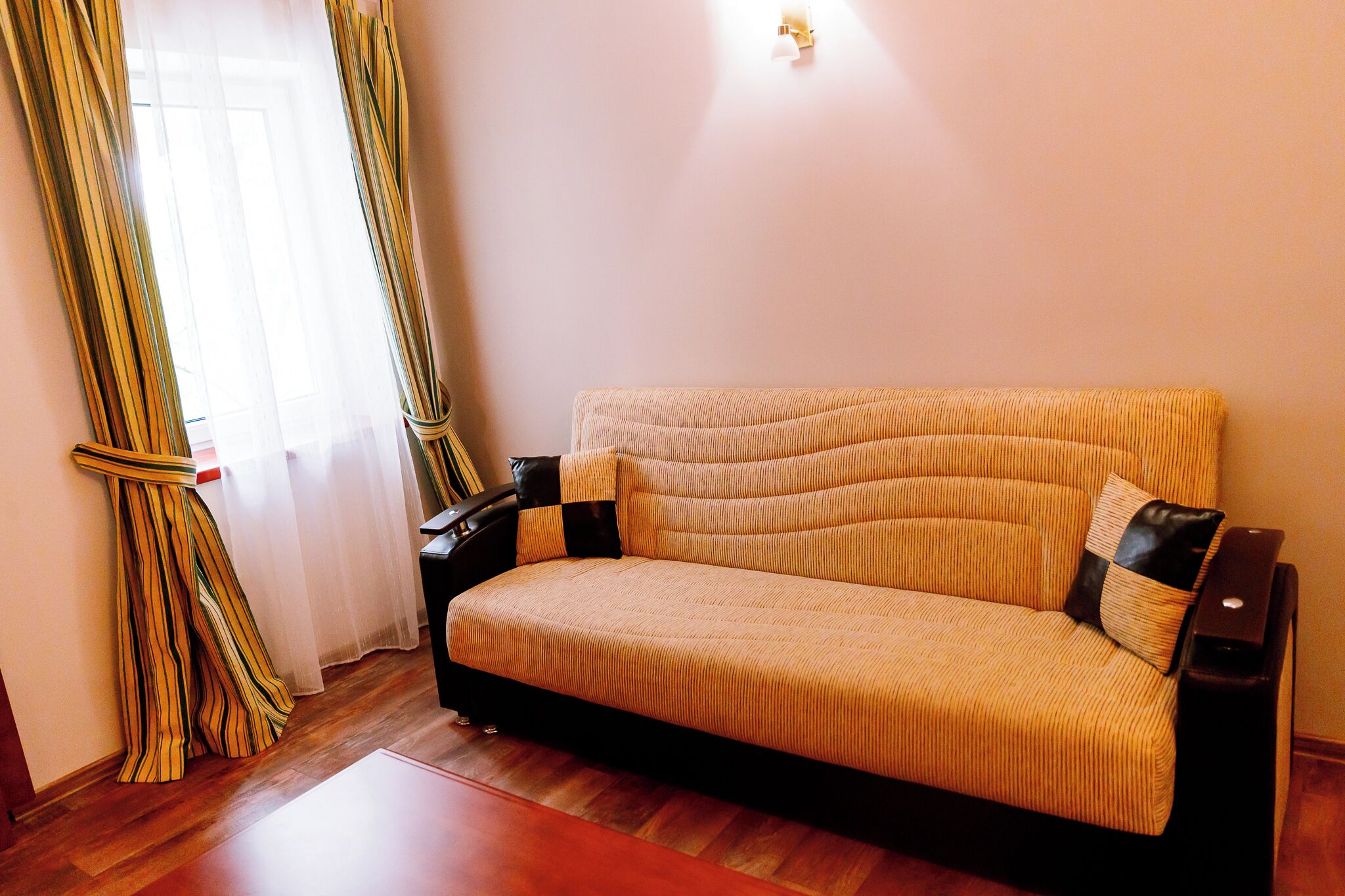 Ein Sofa mit gemustertem Bezug, einer schwarzen Armlehne und einem Kissen mit Streifenmuster.