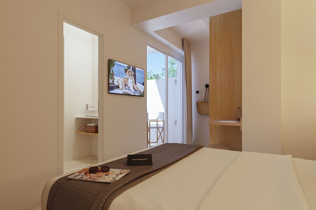 Ein Hotelzimmer mit einem Bett, einem an der Wand befestigten Fernseher, einer kleinen Sitzecke mit einem Sessel und einem Holzschrank.