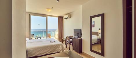 Une chambre d’hôtel avec un lit, un bureau et une grande fenêtre donnant sur la mer.