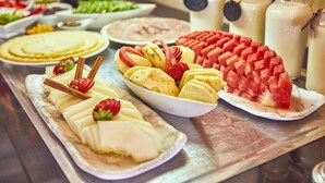 Un buffet proposant divers plats, notamment des tranches de bananes, des fraises et de la pastèque.