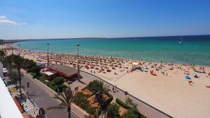 Une plage bordée d’une route, des palmiers et un ciel bleu azur.
