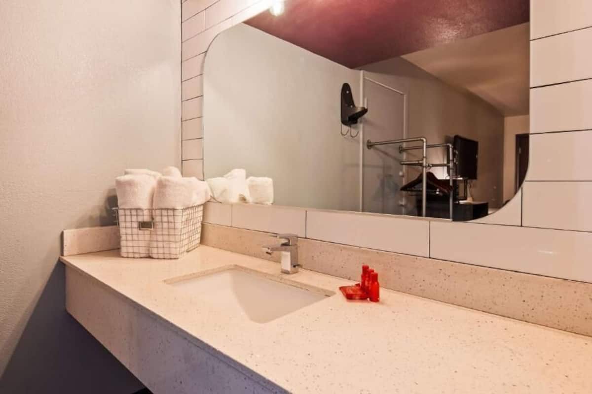 A bathroom with a white sink, a mirror, and a towel rack.