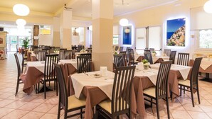 A spacious restaurant with multiple tables and chairs, large windows with a view, and a clean, modern interior. - Roy Hotel (Silea)