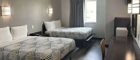 A hotel room with two beds, a desk, a chair, and a window with curtains.