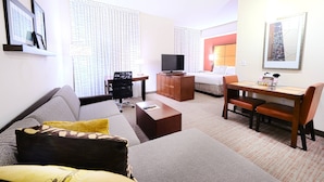 Une chambre d’hôtel équipée d’un canapé, d’une table basse, d’une télévision, d’un bureau avec une chaise et d’un lit.