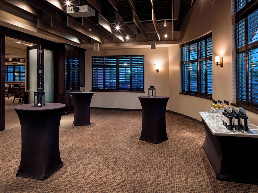 A conference room with round tables, a projector, and a window with blinds.