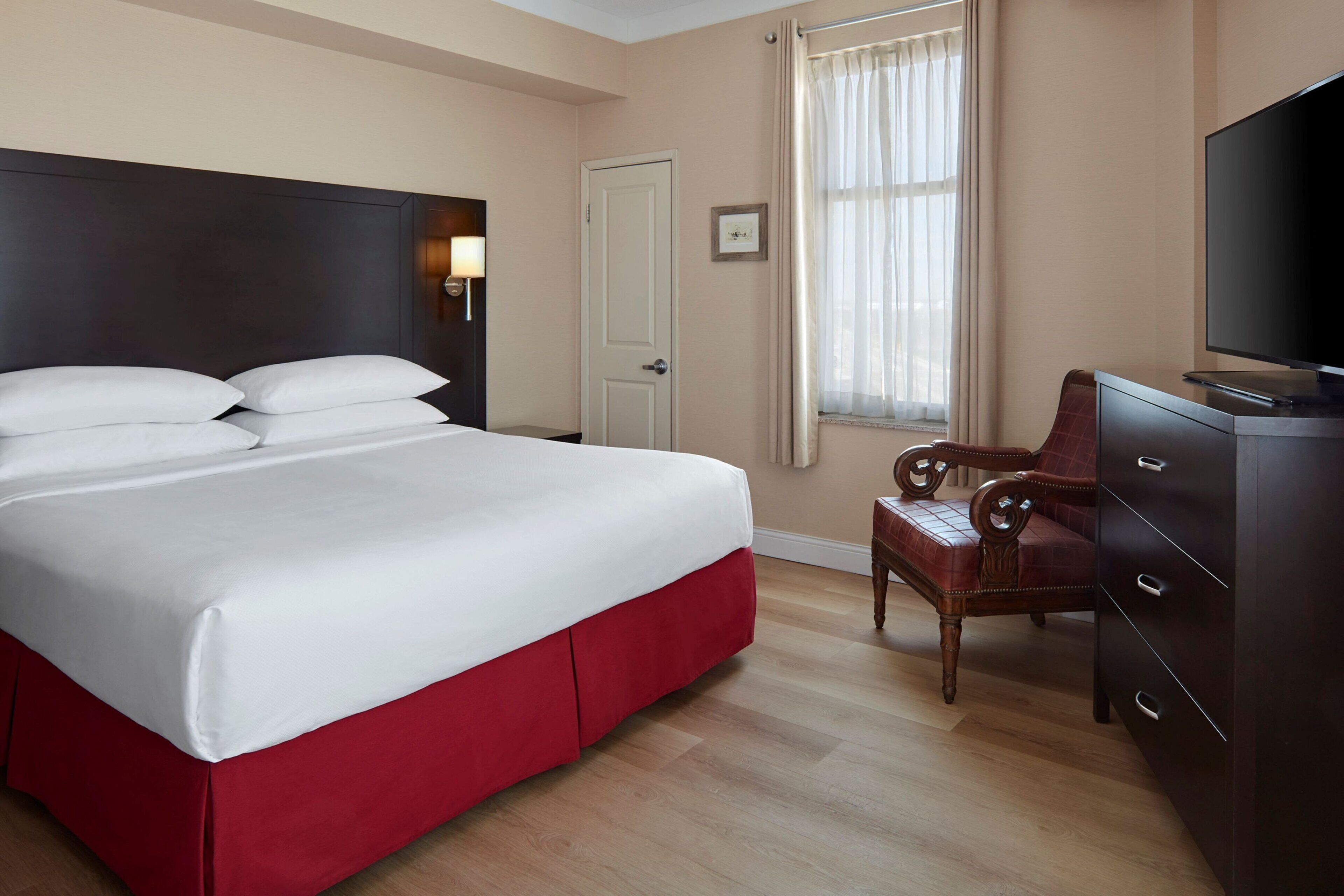 Habitación de hotel con una cama grande, televisión, escritorio y silla.
