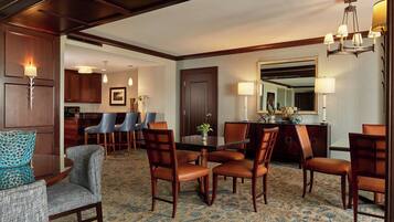 A hotel dining area with a round table, wooden chairs, and a carpeted floor.