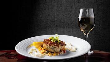 A plate of food with a glass of white wine on a dark background.