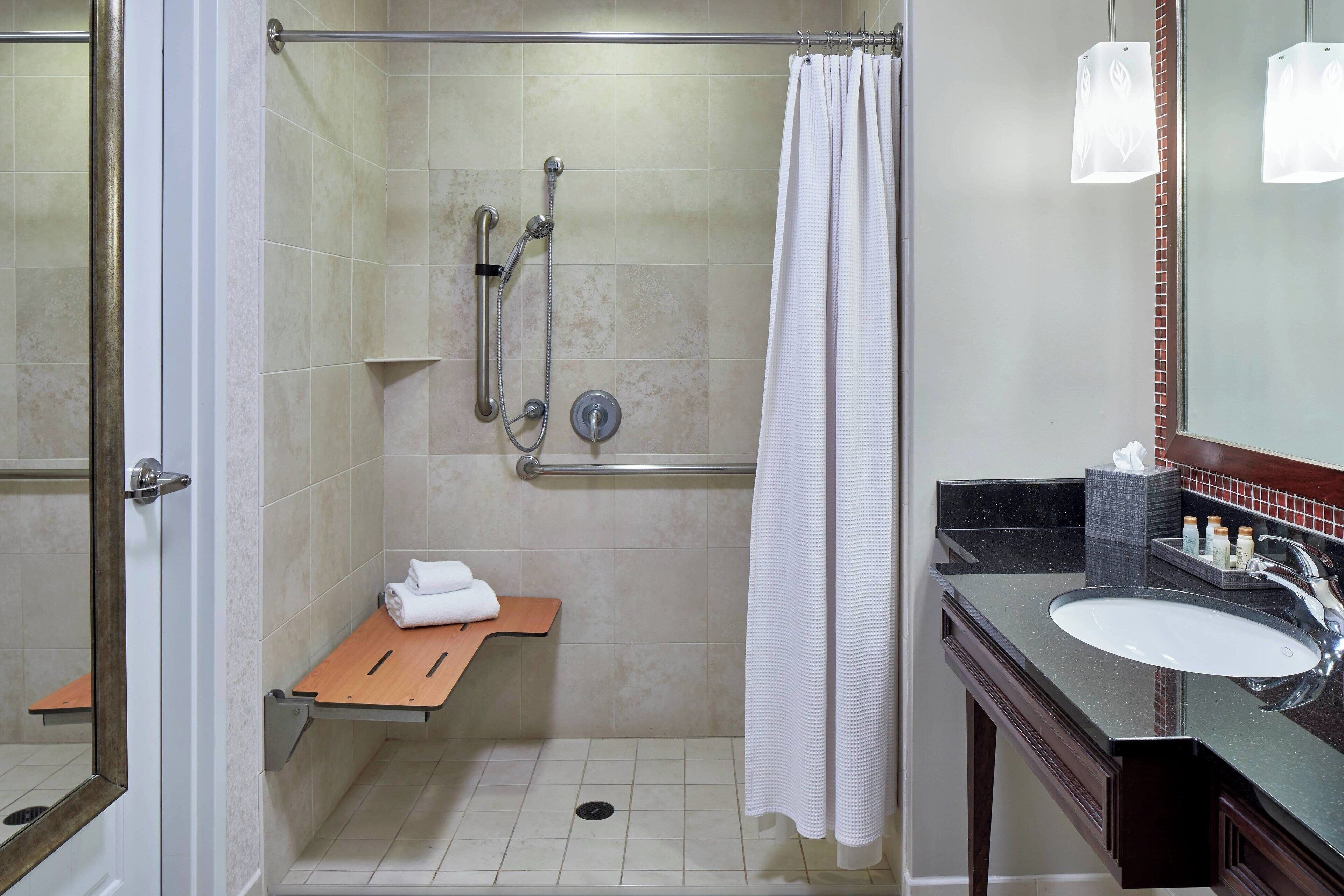 A modern bathroom with a walk-in shower, a glass door, a vanity with a sink, and a towel rack.