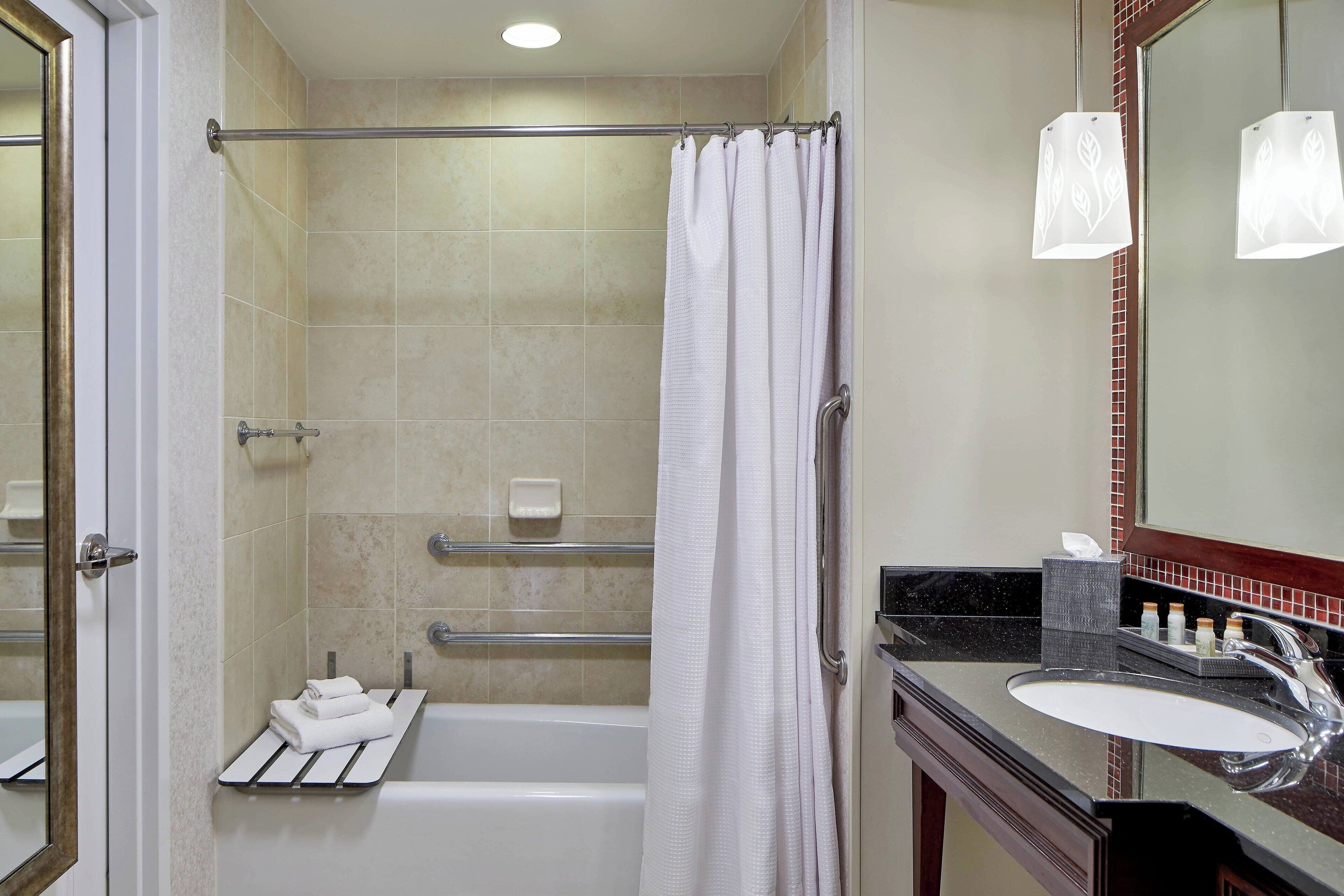 A bathroom with a bathtub, a shower curtain, a towel rack, a sink, and a mirror.