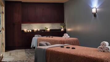 Relax in a serene spa room with two massage tables, a soothing ambiance, and a touch of greenery.