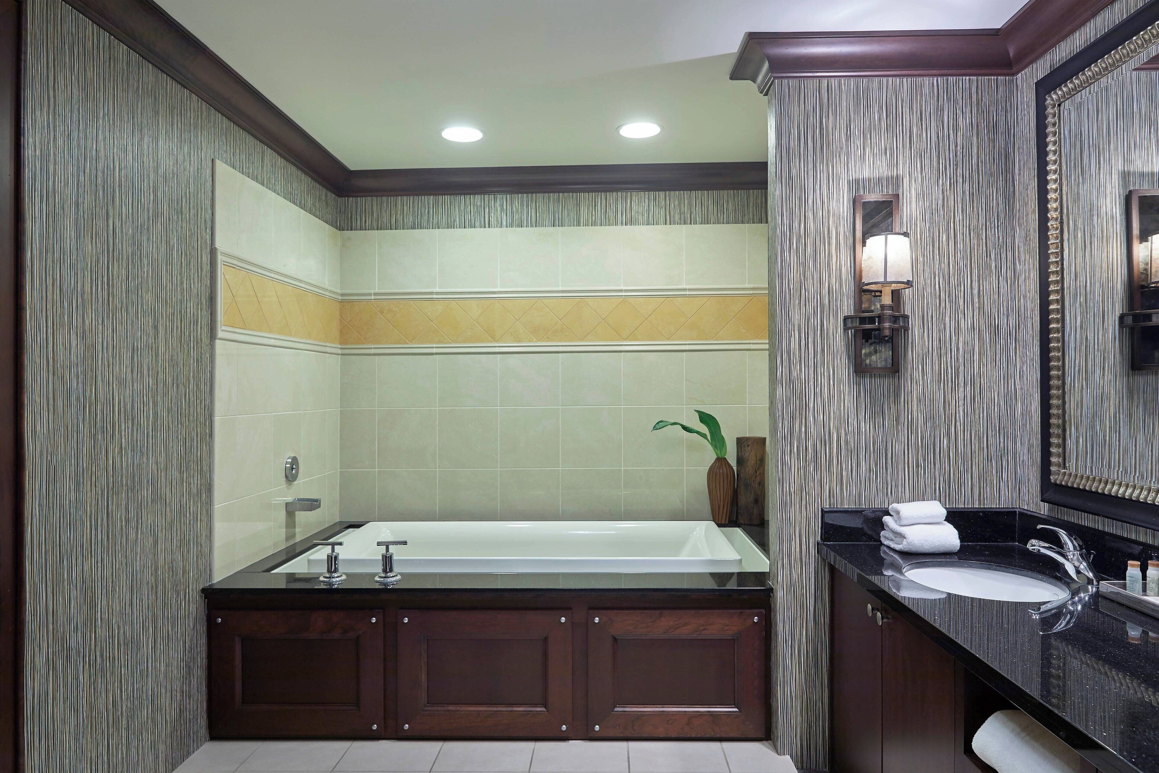 A modern bathroom with a large bathtub, a separate sink, and a mirror.