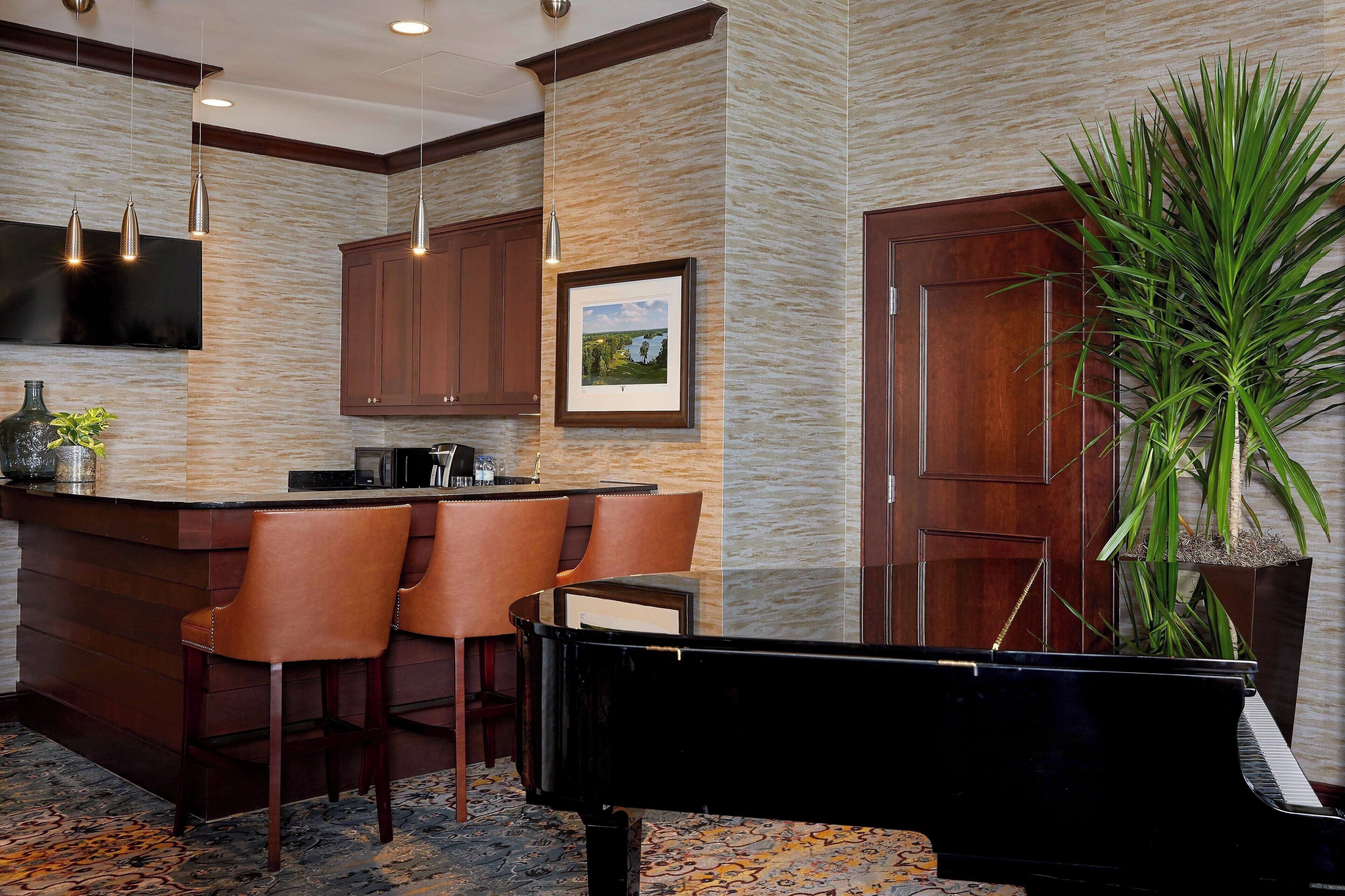 A bar area with a piano, wooden cabinets, and a large potted plant.