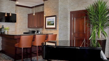 A bar area with a piano, wooden cabinets, and a large potted plant.