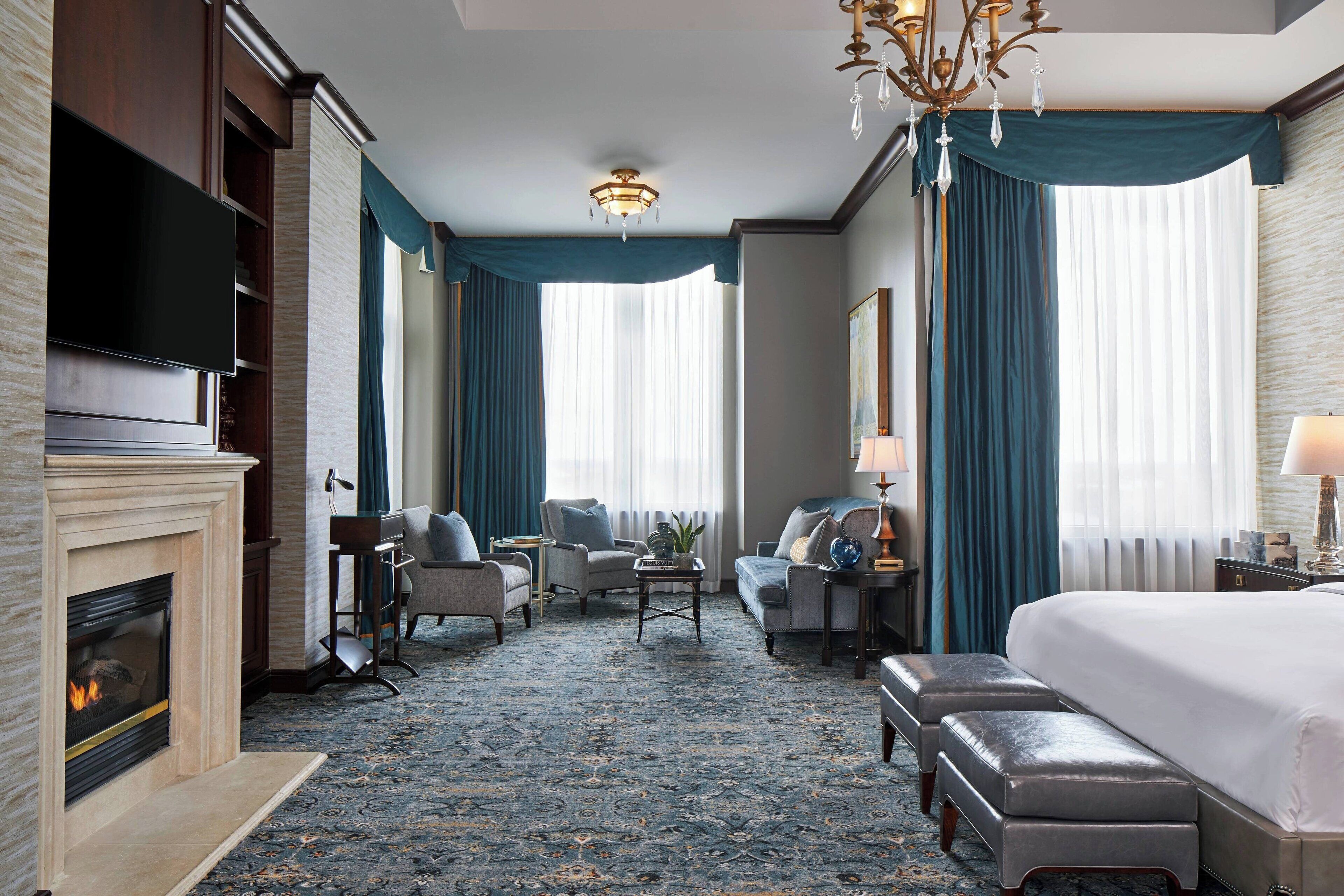 Habitación de hotel con chimenea, televisión, una cama grande, zona de estar con una mesita de café y candelabro.