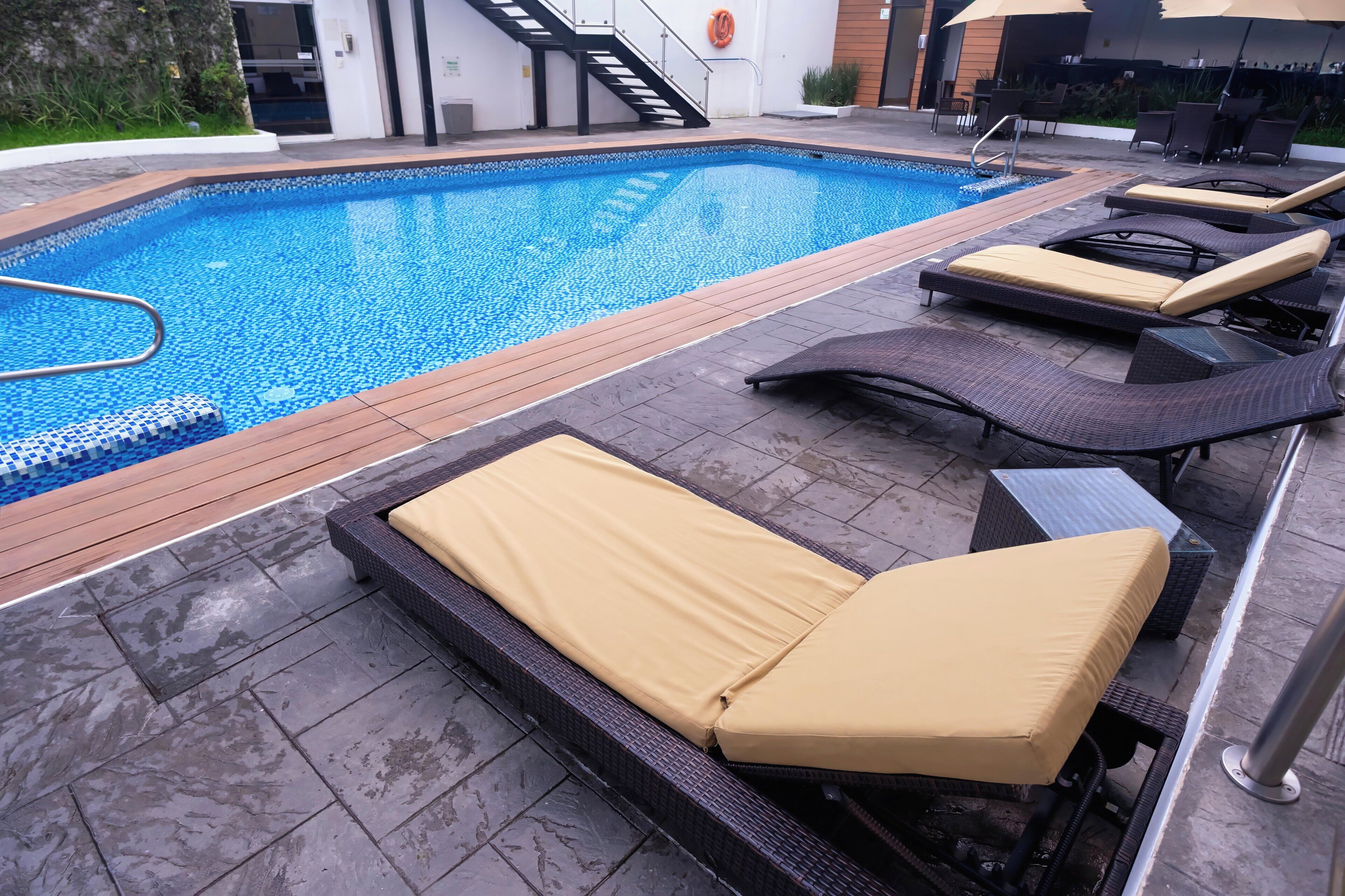 Una piscina con sillones de descanso y una terraza de madera.