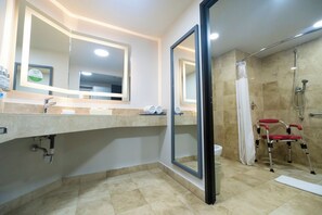 Un baño moderno con un espejo grande, una ducha y una silla de ruedas roja.