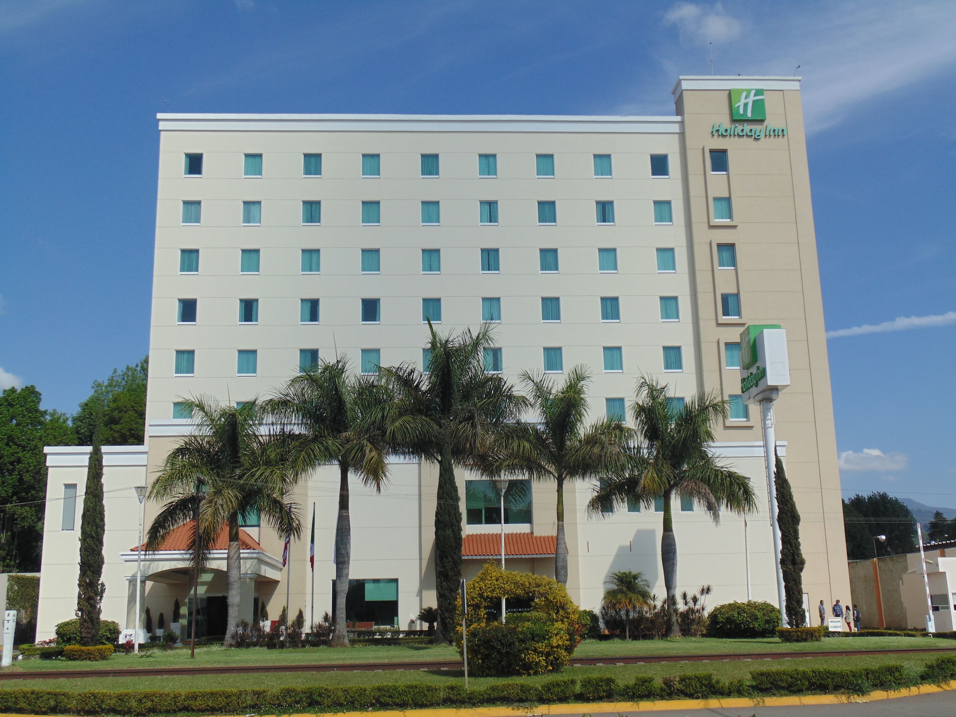 A Holiday Inn hotel building with a symmetrical facade, multiple windows, and a prominent green logo.