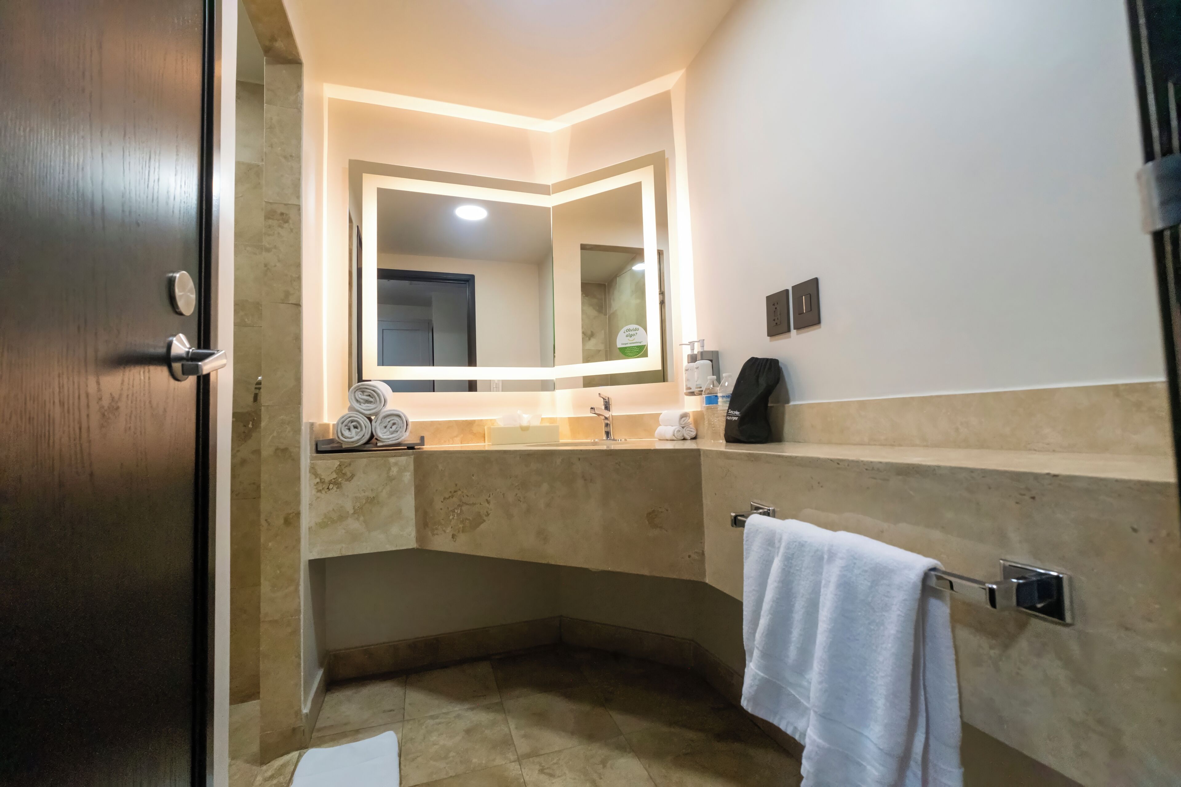 A modern bathroom with a large mirror, a towel rack, and a sink.