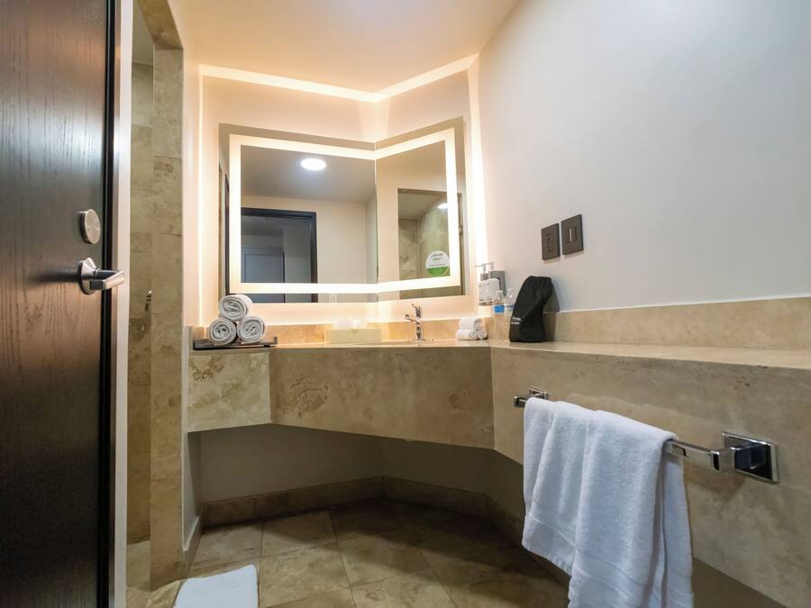 A modern bathroom with a large mirror, a towel rack, and a sink.