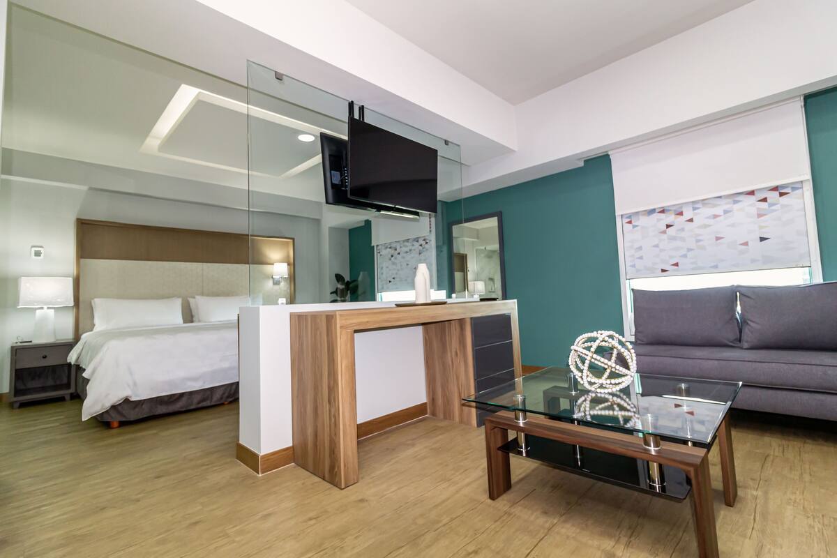 Una habitación de hotel moderna con cama, escritorio, sofá y televisión.