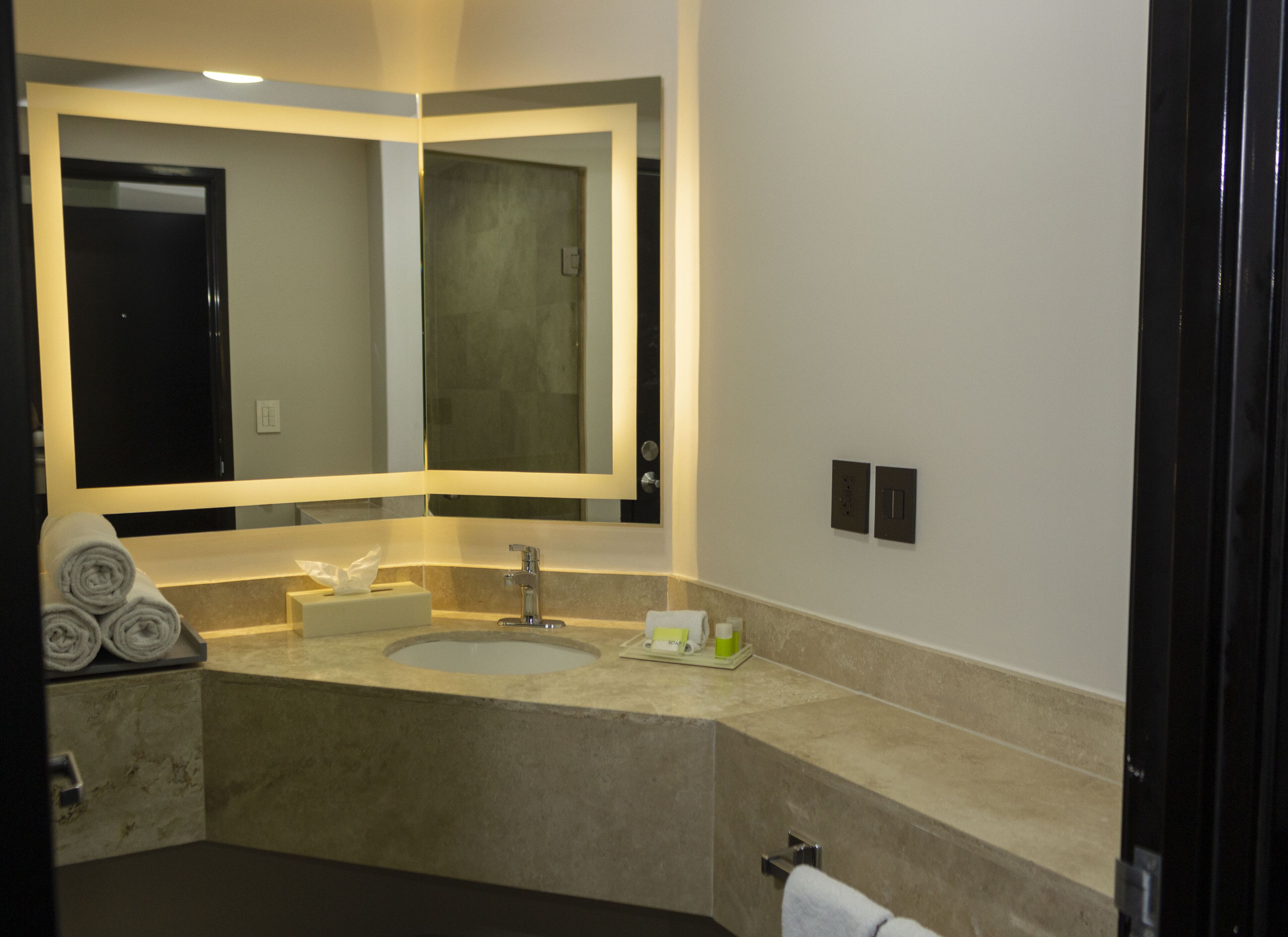 Un baño moderno con un espejo grande, dos lavamanos y un perchero para toallas.