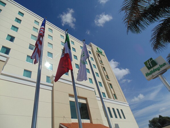 Un edificio de hotel con varias banderas, incluyendo la bandera estadounidense, y un cartel que indica que es un Holiday Inn.