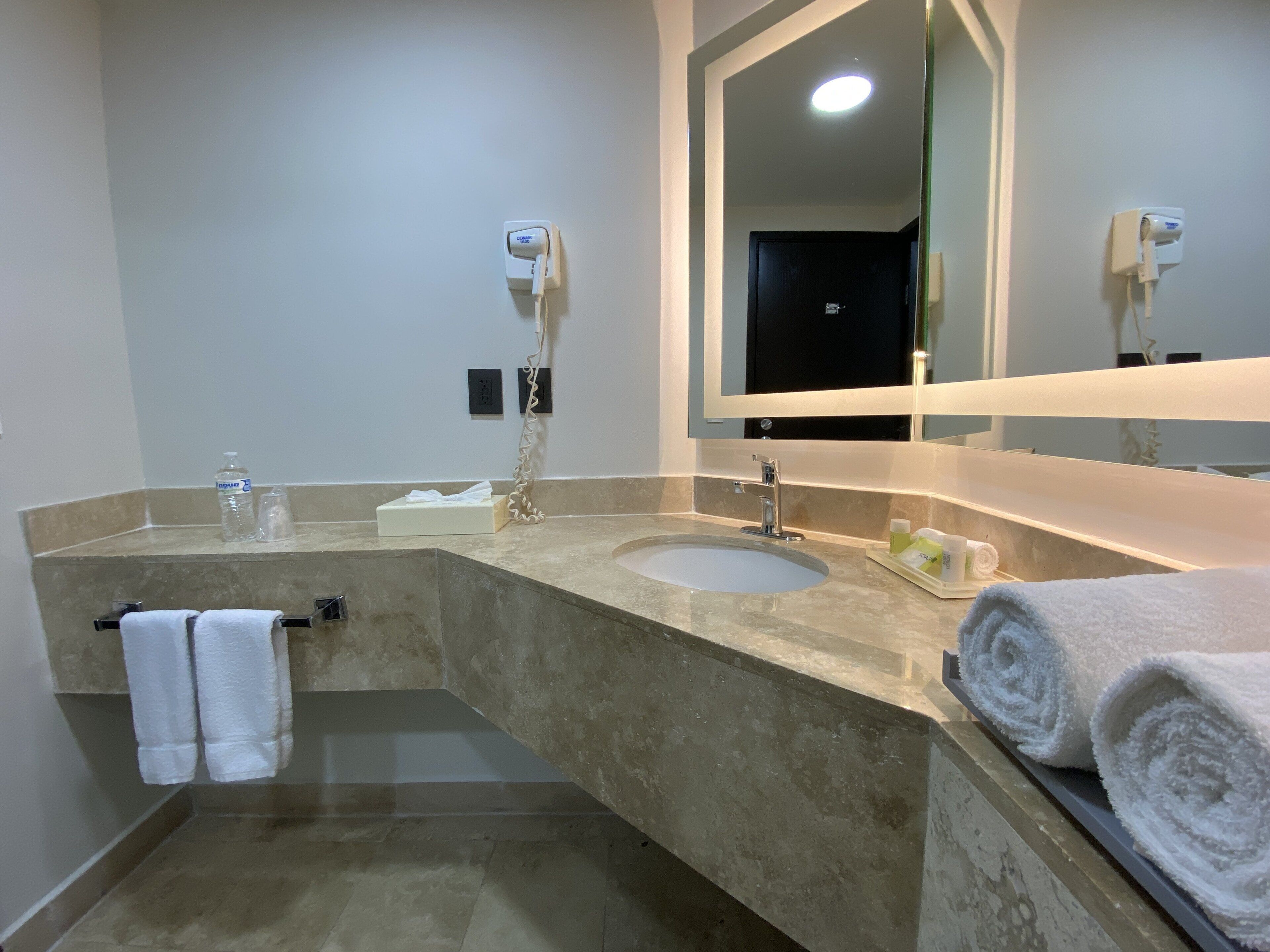 Un baño con dos lavamanos, un espejo grande y un perchero para toallas.