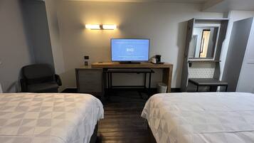 A hotel room with two beds, a desk with a computer, a chair, and a mirror.