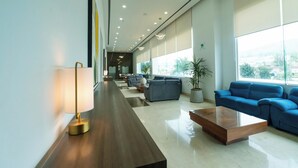 Un vestíbulo moderno con un mostrador de recepción alargado, zona de estar y grandes ventanales con vistas a la ciudad.