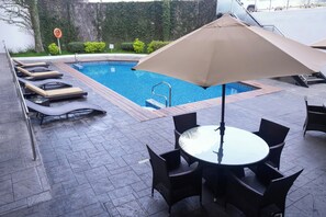 Una piscina con sillas de descanso y una mesa con sillas.