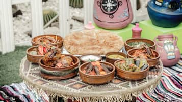 A variety of dishes served on a woven tablecloth, with a flatbread and several bowls containing different foods.