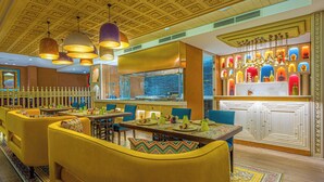 Un restaurant avec des chaises jaunes, un coin bar et un plafond décoratif.