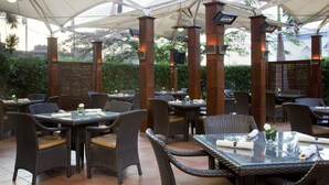 Un espace extérieur aménagé pour les repas, avec des meubles en osier et des parasols.