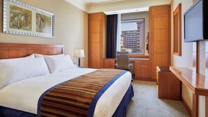 Une chambre d’hôtel avec un grand lit, un bureau, une télévision et des œuvres d’art accrochées au mur.